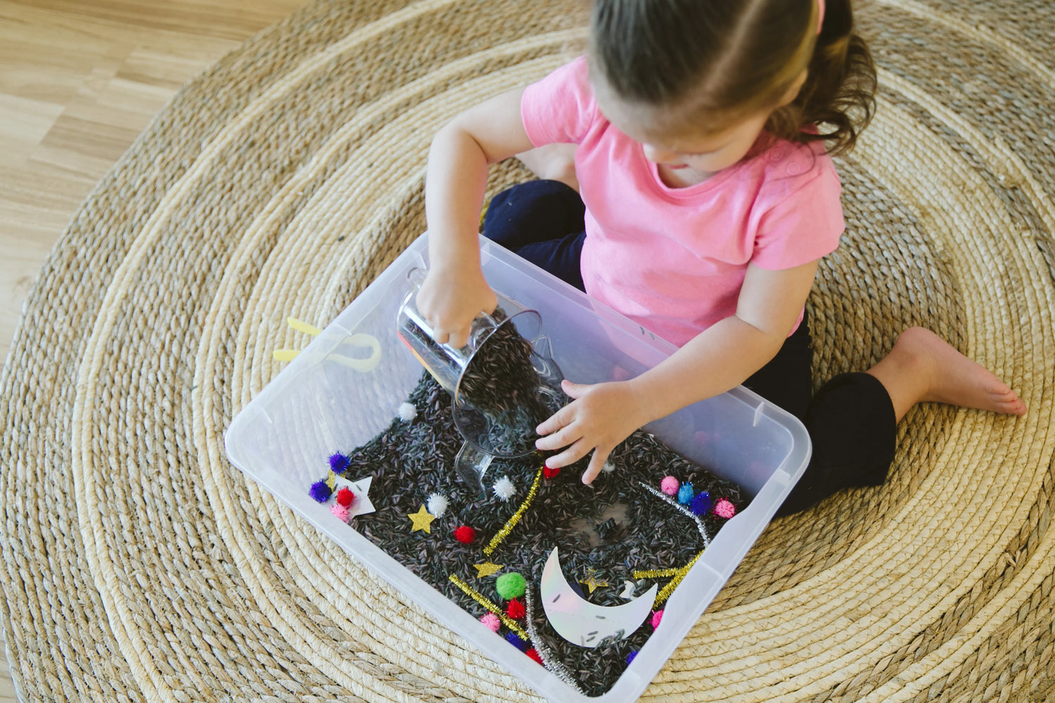 Mom and toddler exploring items in a sensory box together.