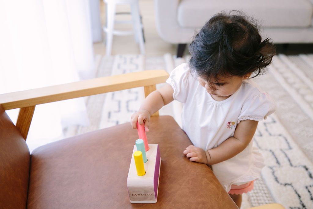 A toddler intently playing with a peg toy, highlighting concentration and focus, relevant to strategies for developing attention span in young children.