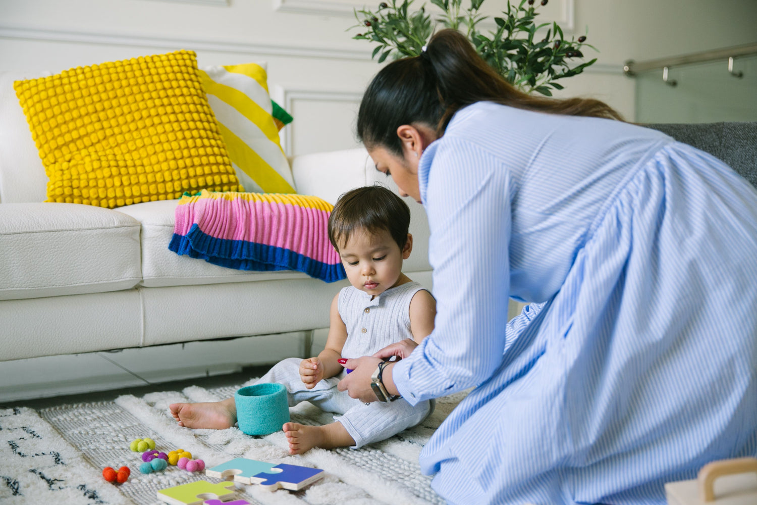 mother guiding toddler in play area with toys 