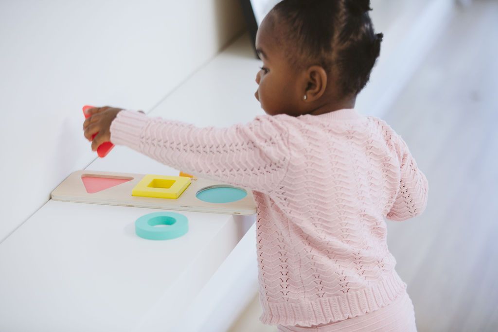 Toddler playing with colorful puzzle pieces, enhancing fine motor skills and hand-eye coordination